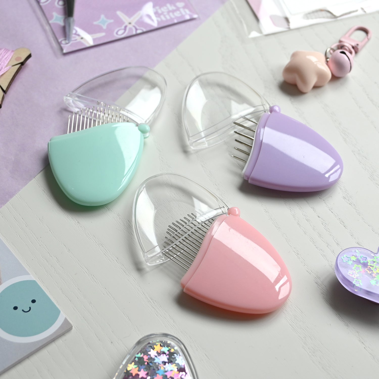 Three john james needle sets in pastel colors on a light surface.