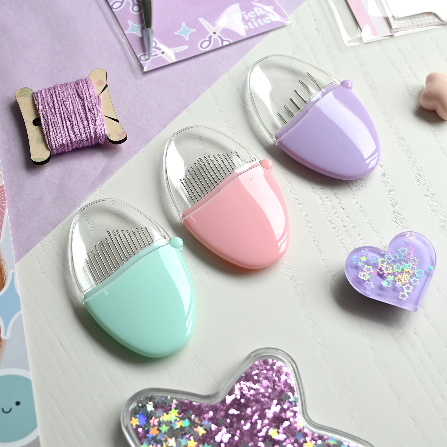 Three sets of John James needle pebbles in pink, purple and green.