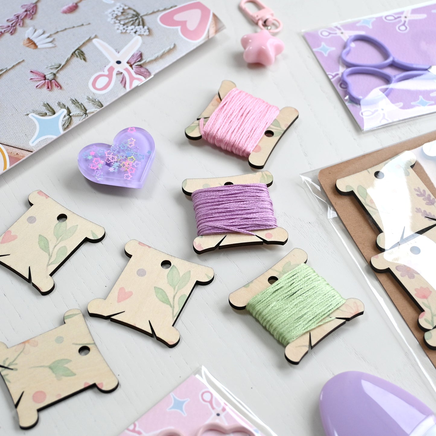 Wooden spools with colorful thread on a white surface with decorative cards and items.