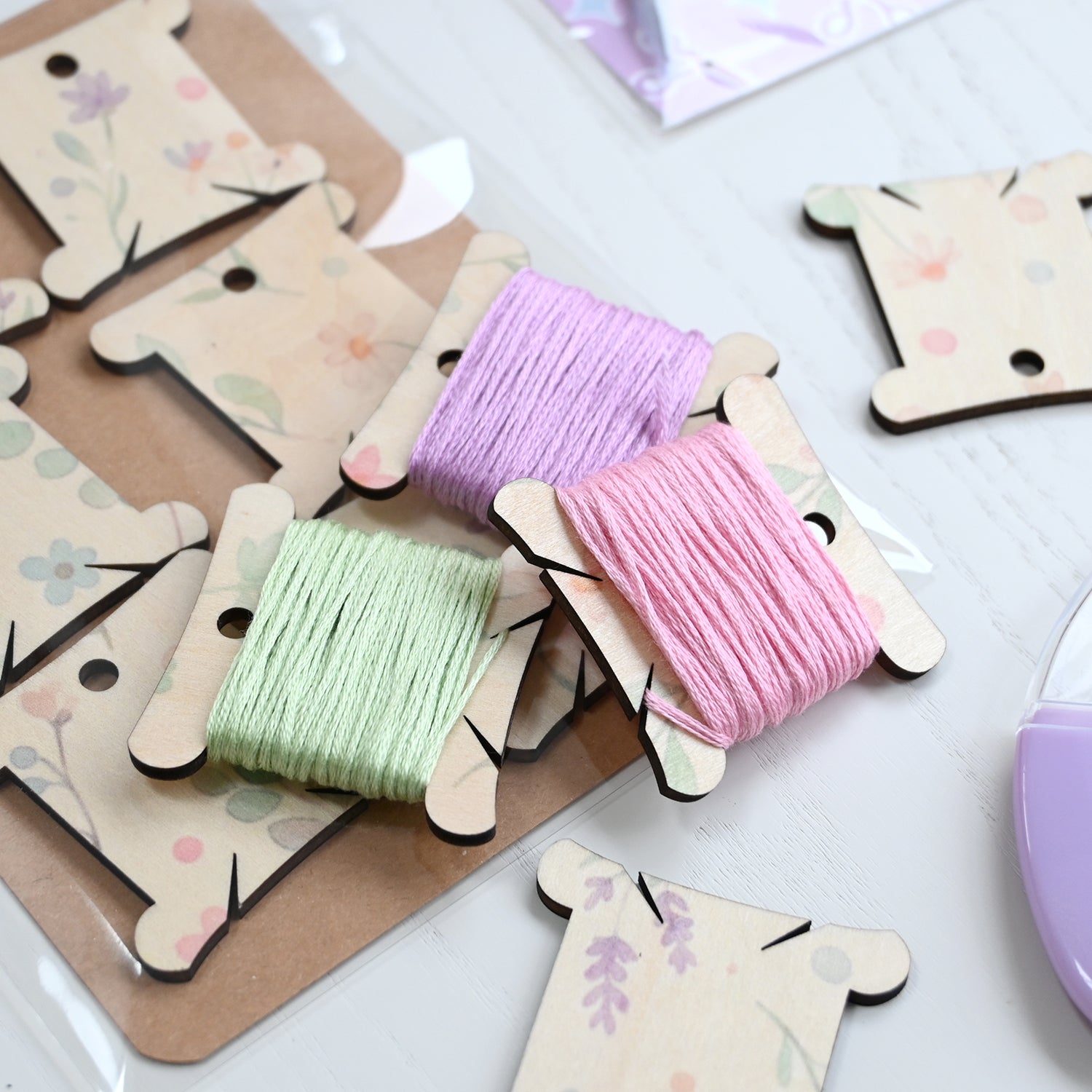 Colorful thread spools on wooden holders on a white surface.