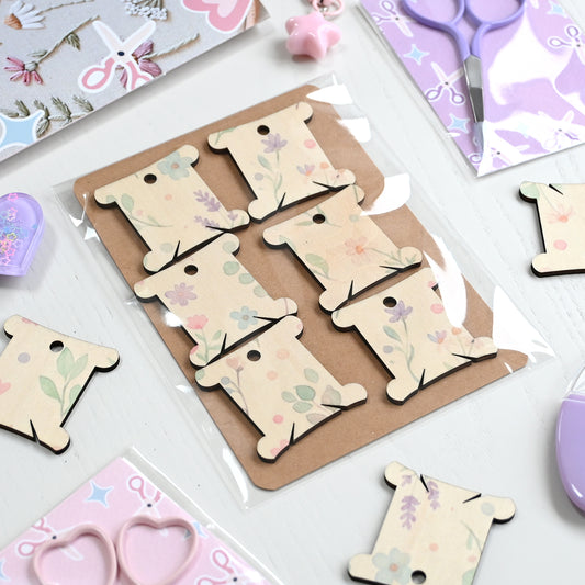 A pack of wooden embroidery thread bobbins printed with a pastel floral pattern.