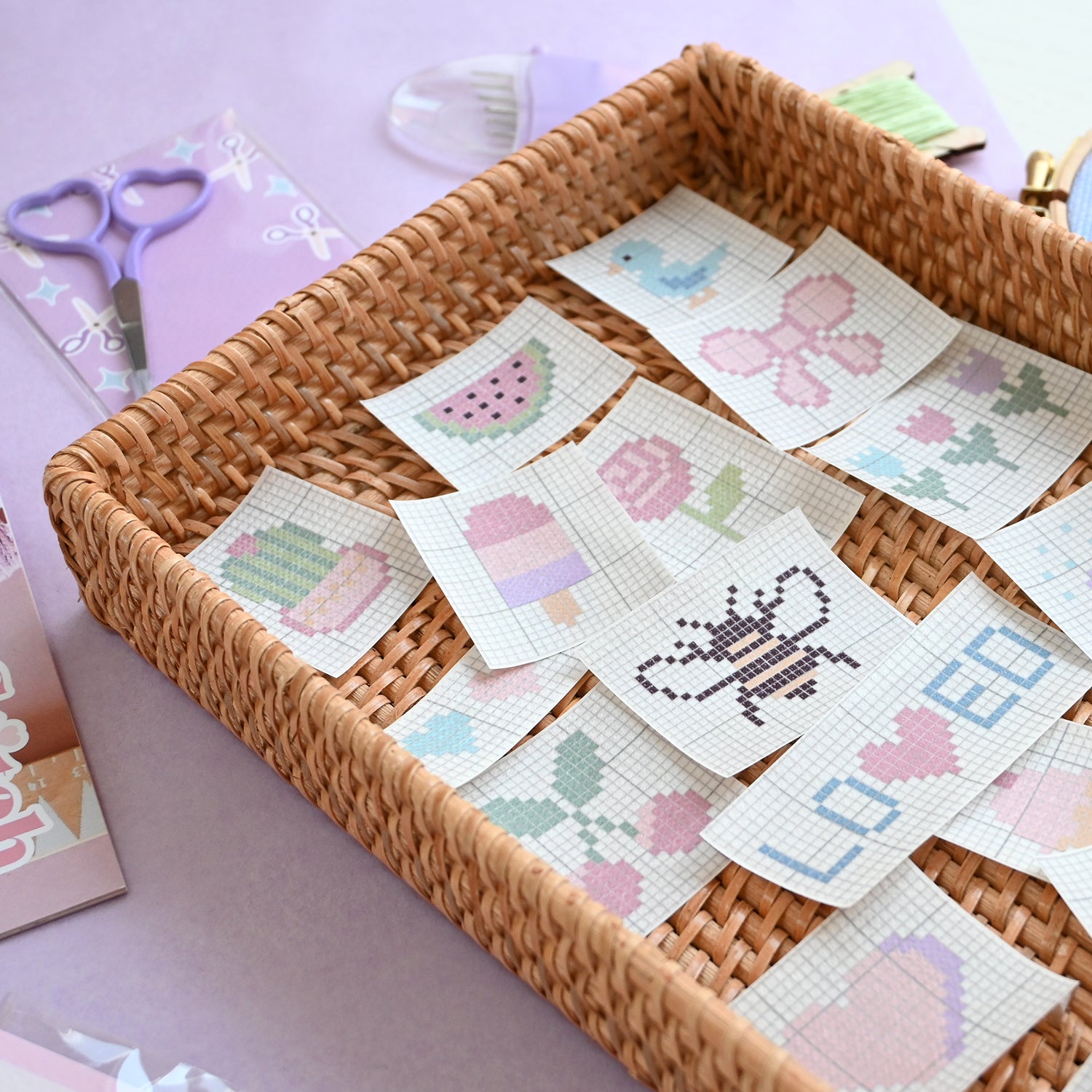 Cross-stitch patches in a woven basket with scissors and fabric in the background.
