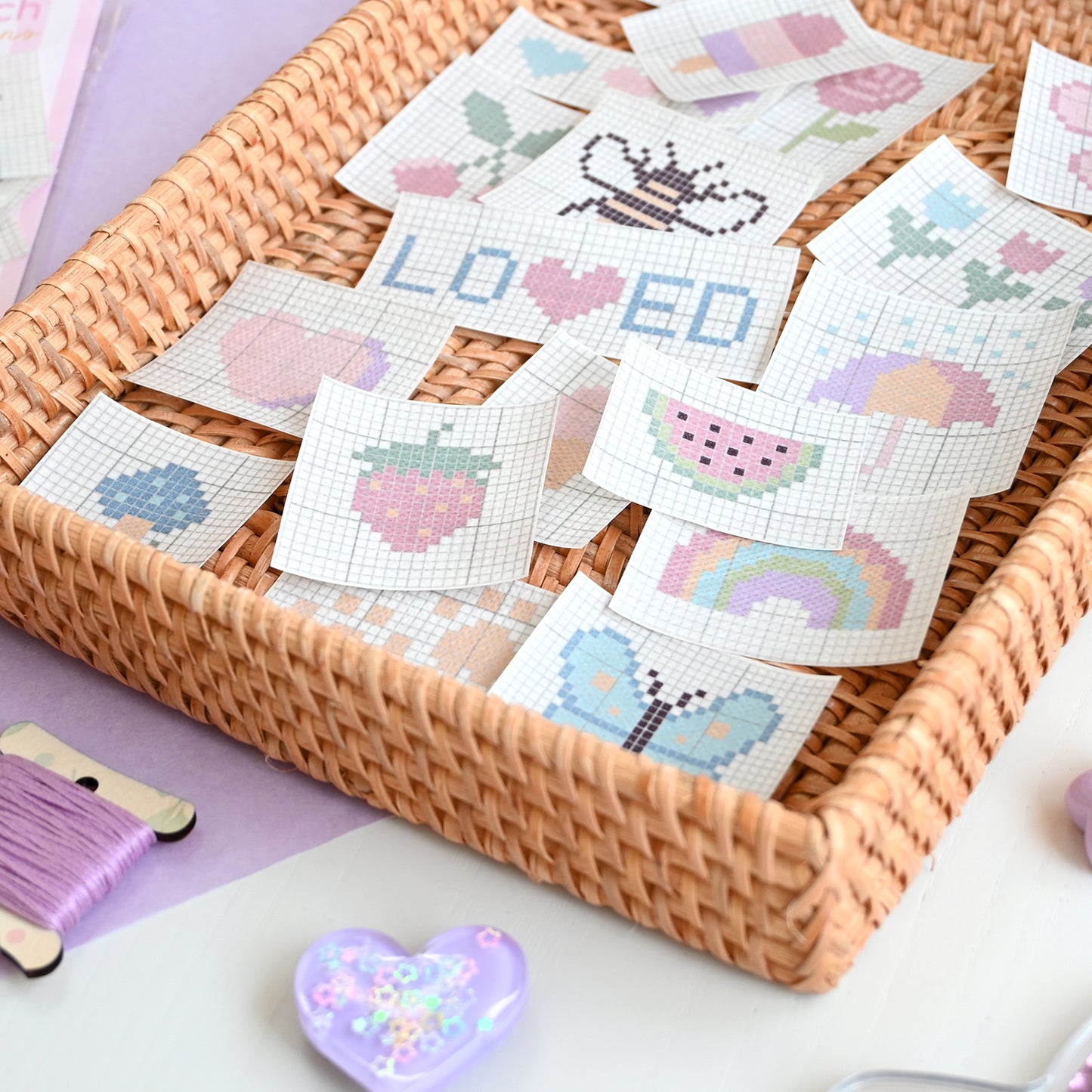 Cross-stitch sulky sticky fabri solvy patches in a woven basket on a light purple surface