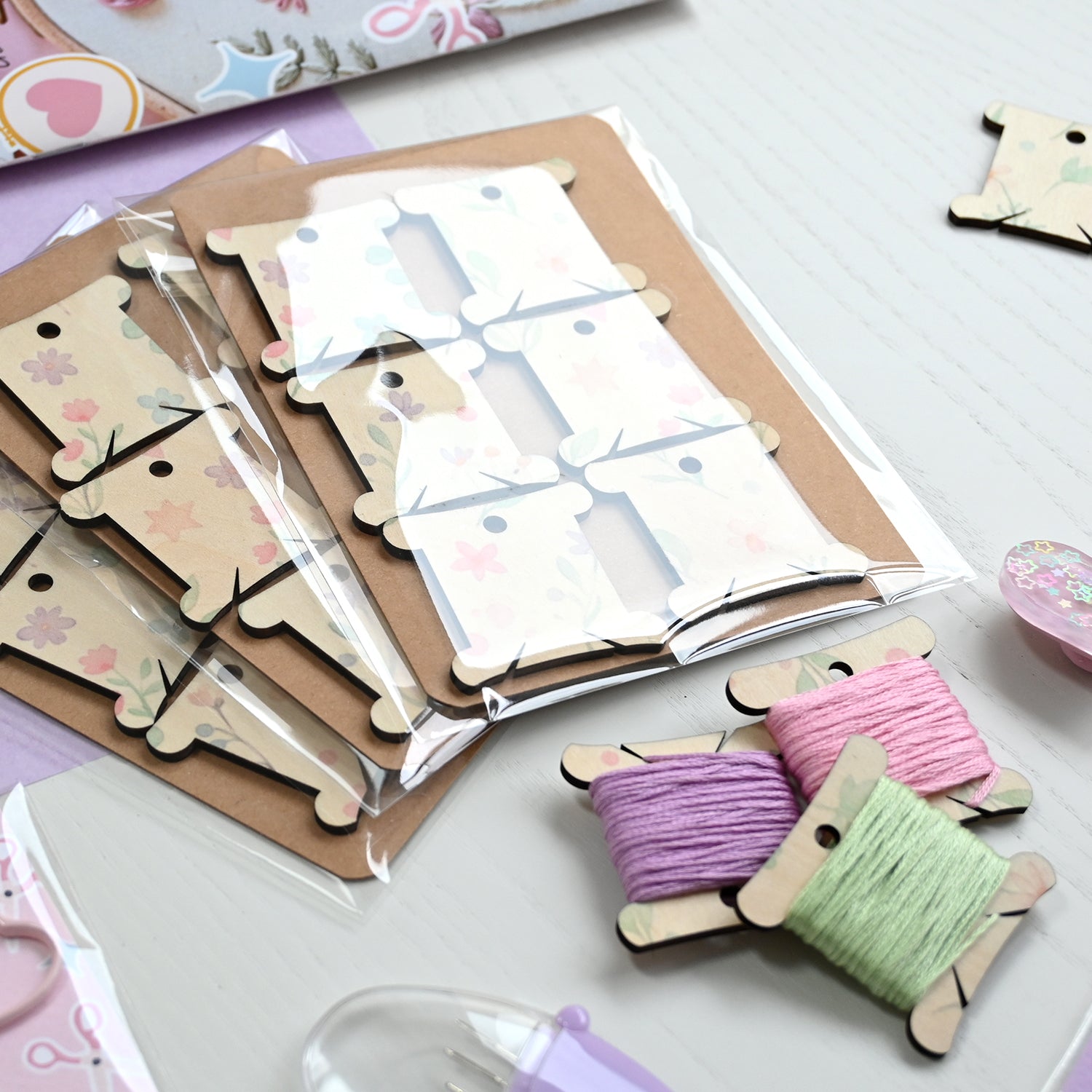 Crafting kit with wooden tags, thread spools, and tools on a white surface